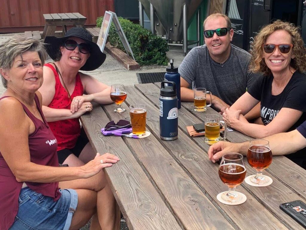 people sitting at an outdoor table at the 19-81 Brewing Co. taproom in Grand Cayman, enjoying beers