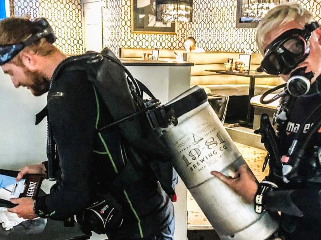 Two divers underwater using a 19-81 beer keg as an air tank